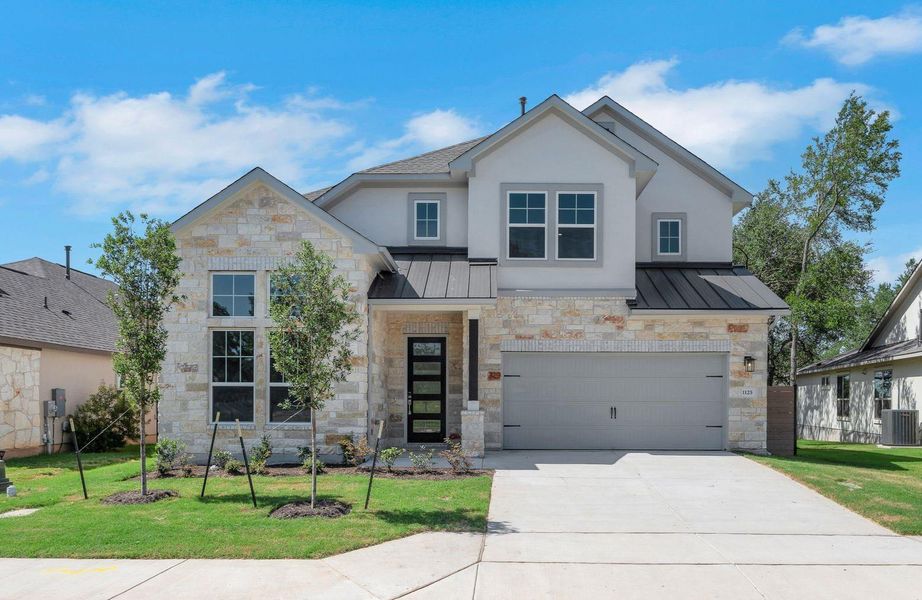 View of front facade featuring a standing seam roof, stone siding, a metal roof, and a front yard