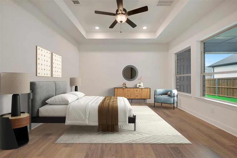 This room features hardwood flooring, a tray ceiling with recessed lighting and a ceiling fan, and large windows providing natural light