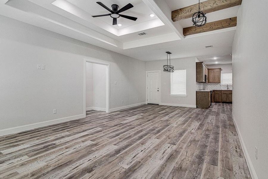 Unfurnished living room with sink, ceiling fan, beamed ceiling, and hardwood / wood-style flooring