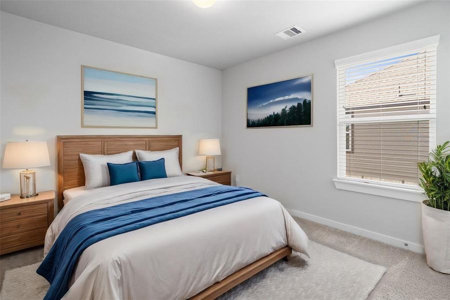 Secondary bedroom features plush carpet, custom paint, lighting, and large windows with privacy blinds.