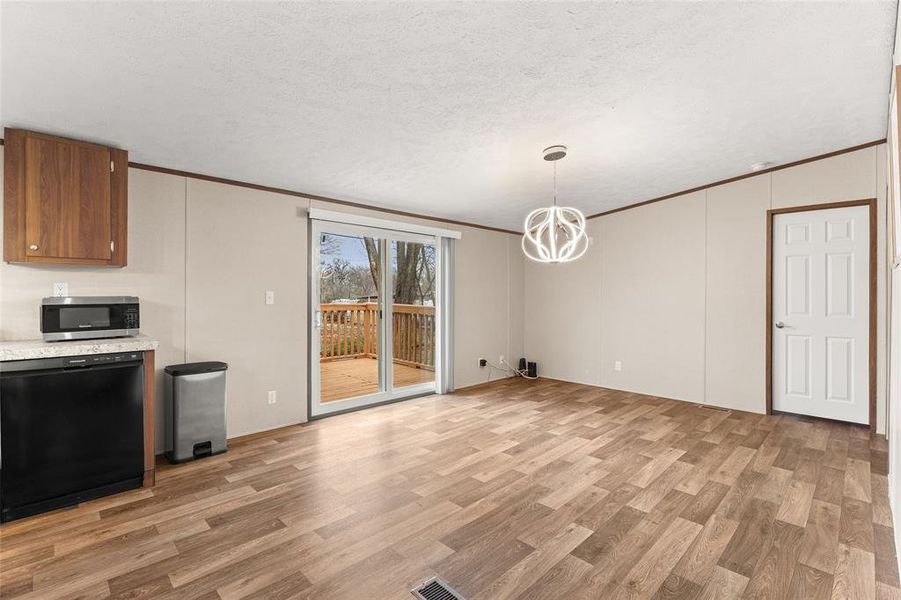 Unfurnished dining area with light wood finished floors, suspended lighting, a textured ceiling, and ornamental molding