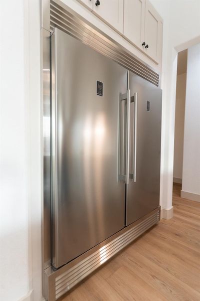 Detailed view of light wood-style flooring, built in refrigerator, and white cabinets Detailed view of light wood-style flooring, built in refrigerator, and white cabinets