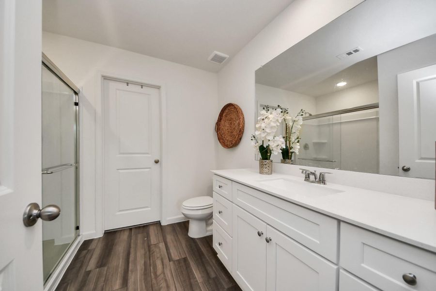 This primary bathroom has a large walkiin shower and plenty of counter and cabinetry.