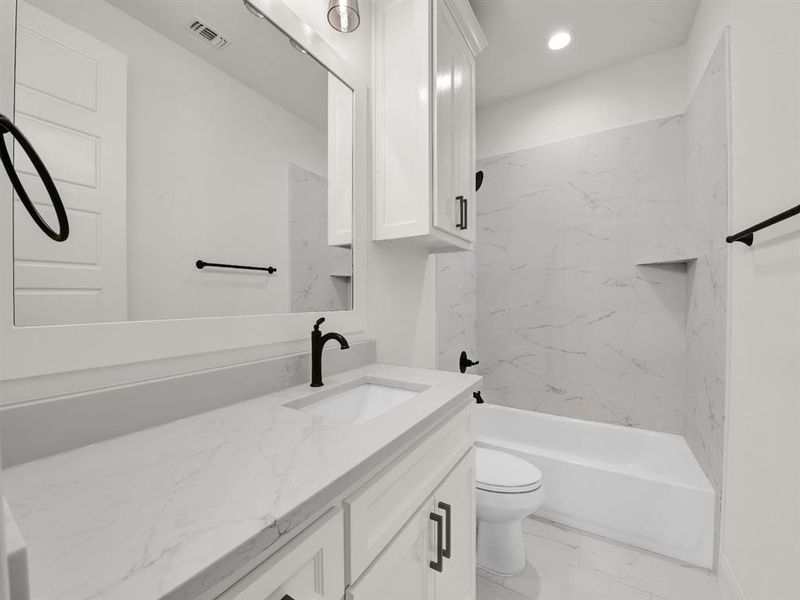Full bathroom with vanity, toilet, marble look tiles, tub / shower combination, and recessed lighting Full bathroom with vanity, toilet, marble look tiles, tub / shower combination, and recessed lighting
