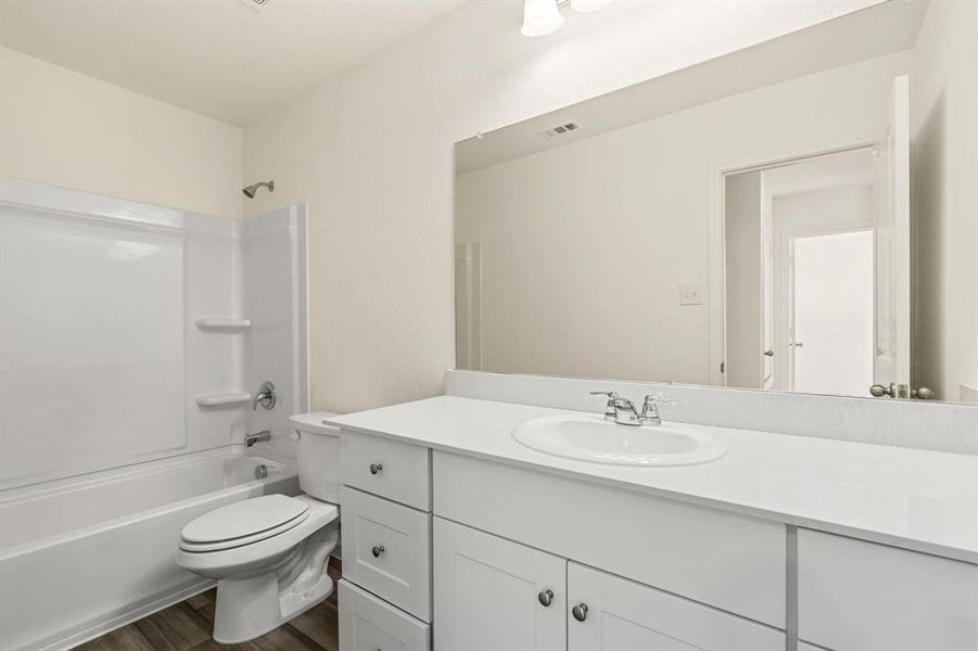 Bathroom featuring vanity, bathing tub / shower combination, and dark wood-type flooring Bathroom featuring vanity, bathing tub / shower combination, and dark wood-type flooring