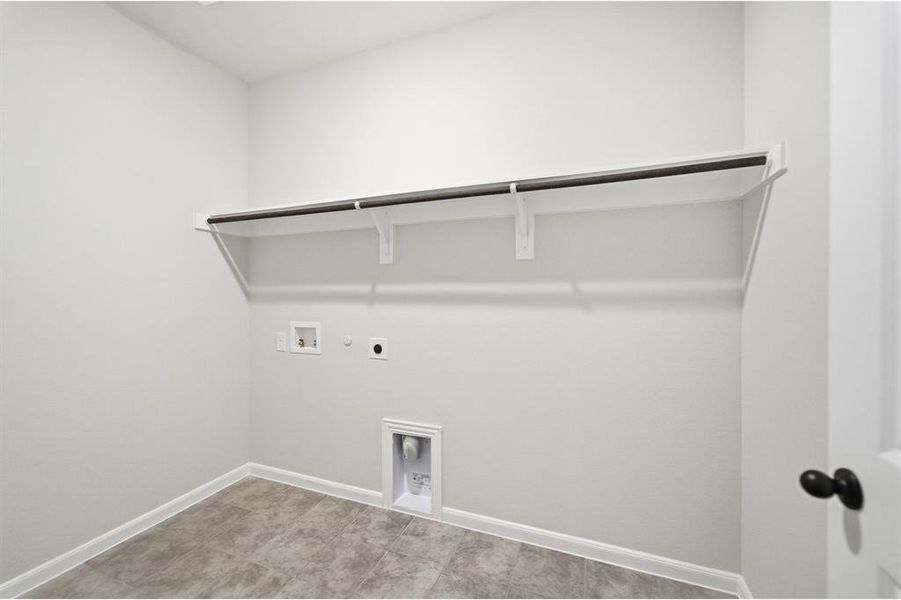 Dedicated utility space featuring a built-in shelving unit with hanging rod, durable tile flooring, and essential appliance hookups Dedicated utility space featuring a built-in shelving unit with hanging rod, durable tile flooring, and essential appliance hookups