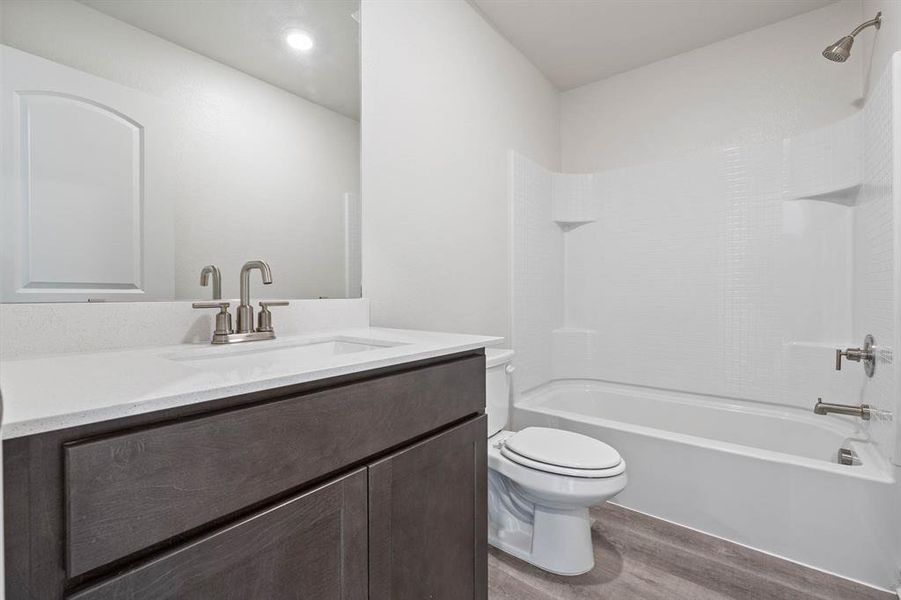 Full bathroom with washtub / shower combination, hardwood / wood-style flooring, toilet, and vanity