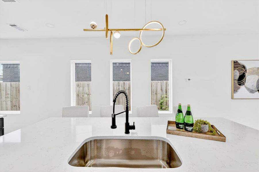 Kitchen island featuring a stainless steel undermount sink and a matte black gooseneck faucet
