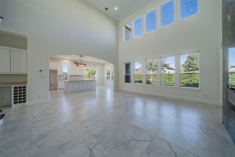 Unfurnished living room featuring arched walkways, light marble finish floors, and a towering ceiling Unfurnished living room featuring arched walkways, light marble finish floors, and a towering ceiling