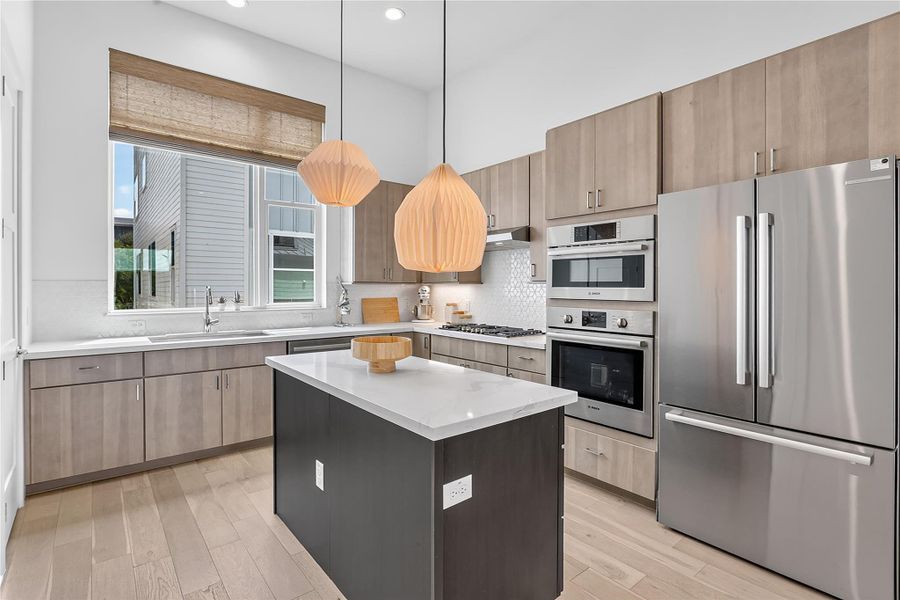 A well-lit kitchen with sleek wooden cabinetry and a pristine center island awaits.