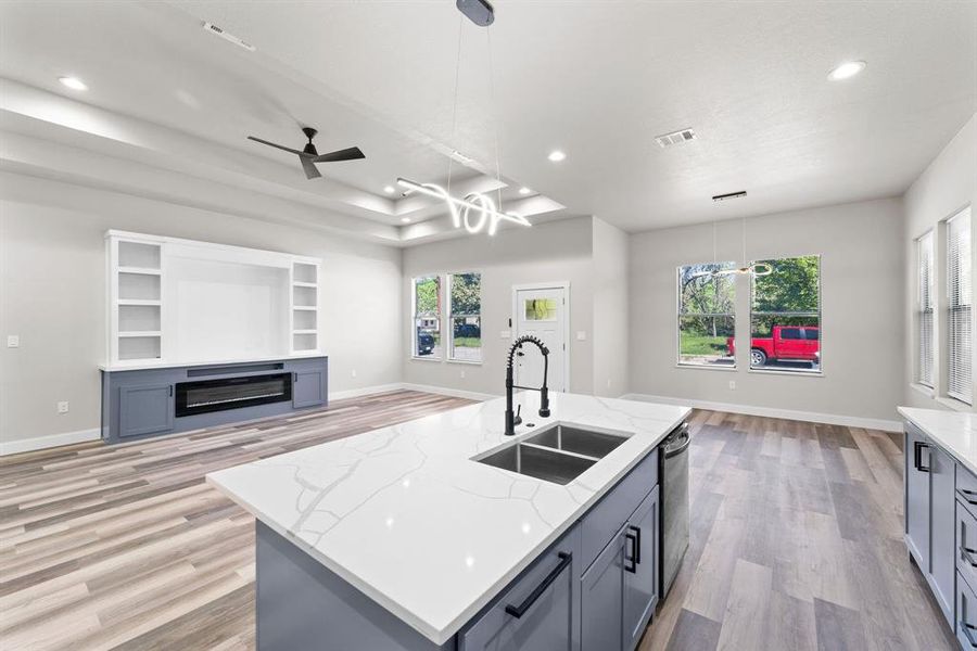 Kitchen with pendant lighting, an island with sink, light wood-type flooring, and sink