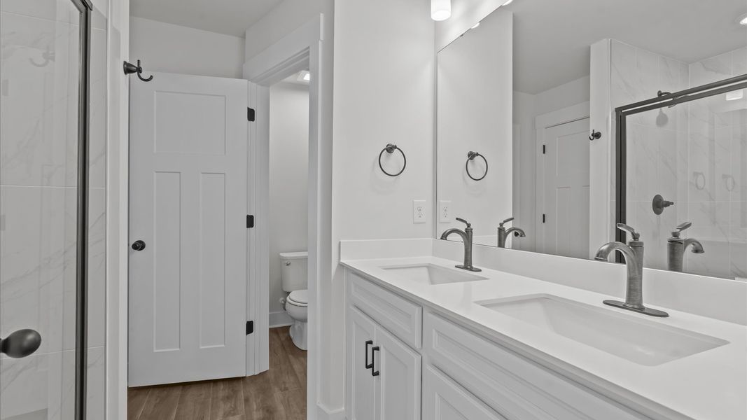 Accomplished design shines in this primary bath with dual vanity and a sleek tiled walk-in shower
