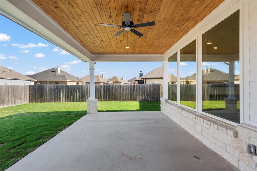 Fenced backyard featuring a ceiling fan, a patio area, and a residential view