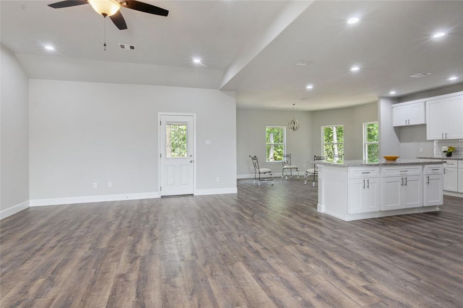 Experience the elegance of this open-concept living area, featuring modern engineered flooring, a ceiling fan, and recessed lighting. The kitchen boasts sleek white cabinetry and granite countertops. Enjoy ample natural light and scenic outdoor views from the spacious dining area.