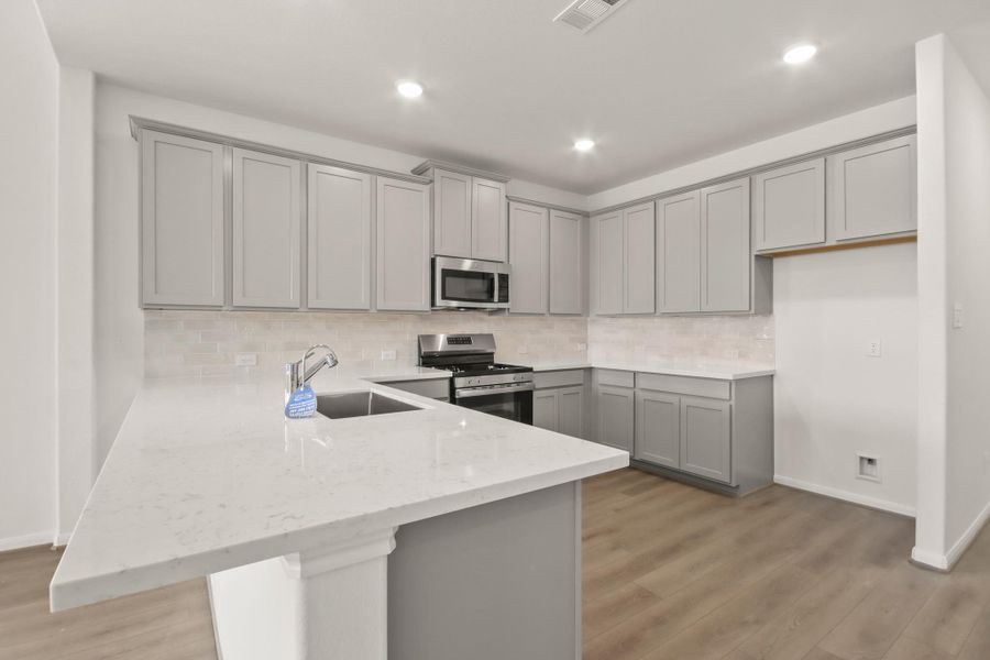 This light and bright kitchen features a large quartz island, white cabinets, a large sink overlooking your family room, recessed lighting, and beautiful backsplash. This light and bright kitchen features a large quartz island, white cabinets, a large sink overlooking your family room, recessed lighting, and beautiful backsplash.