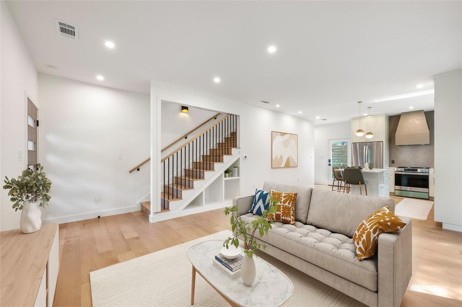 An open-concept living area flows seamlessly into a modern kitchen, featuring a striking staircase with built-in shelving. An open-concept living area flows seamlessly into a modern kitchen, featuring a striking staircase with built-in shelving.