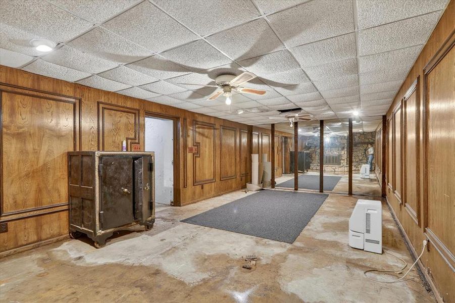 Basement space with wood paneling, drop ceiling, and recessed lighting