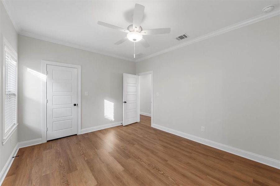 Unfurnished bedroom with ornamental molding, wood finished floors, and ceiling fan Unfurnished bedroom with ornamental molding, wood finished floors, and ceiling fan