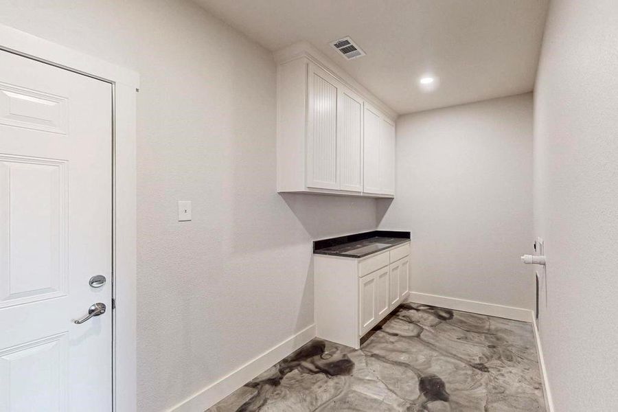 Clothes washing area featuring baseboards and visible vents