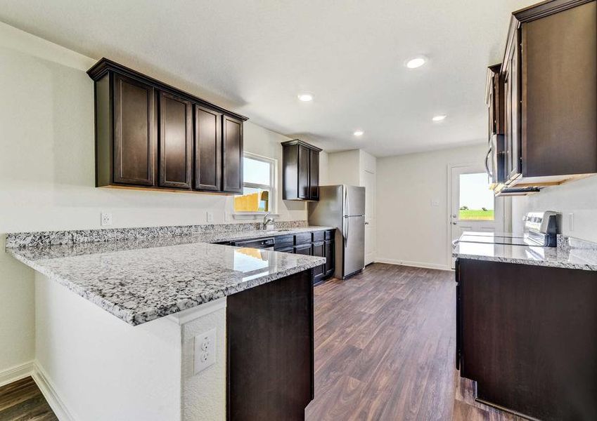 Medina kitchen with vinyl flooring, white framed door, recessed lights, granite countertops and dark brown crown molded cabinets