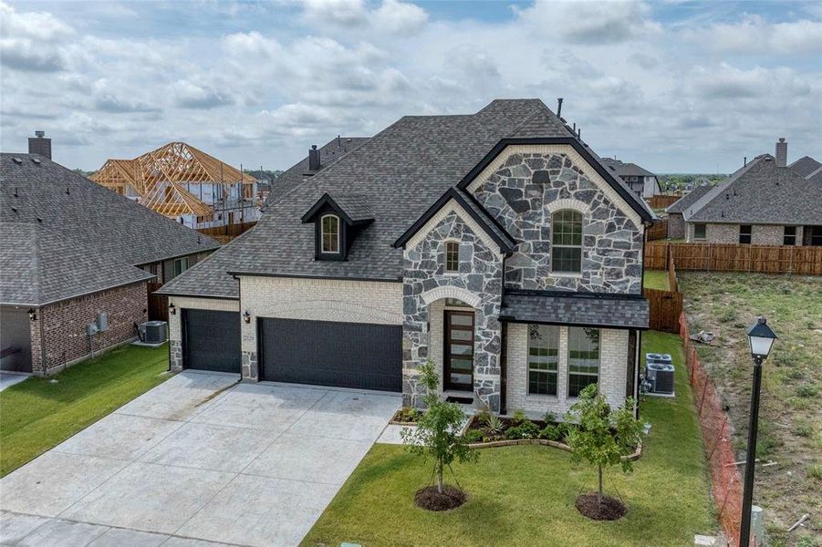 French provincial home with stone siding, brick siding, concrete driveway, and a shingled roof