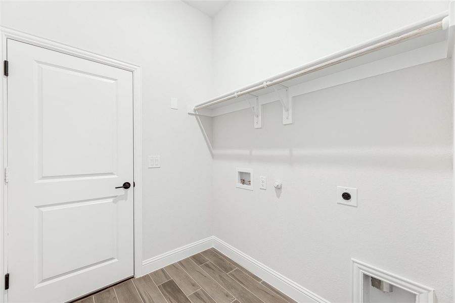 Laundry room with white walls, upper shelf, washer and dryer hookups, and wood-look tile flooring Laundry room with white walls, upper shelf, washer and dryer hookups, and wood-look tile flooring
