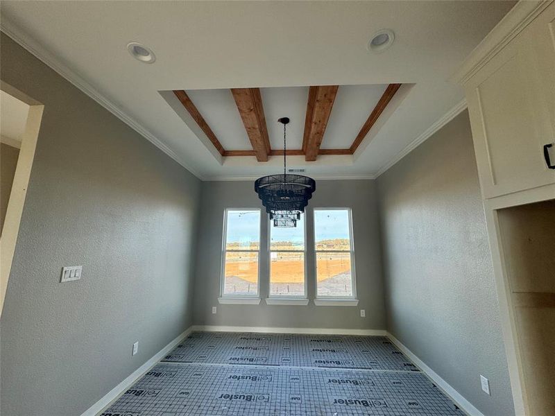 Unfurnished dining area with beamed ceiling, ornamental molding, light tile patterned floors, and an inviting chandelier