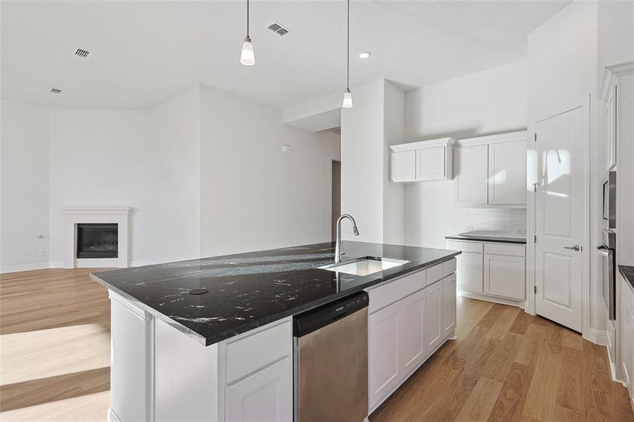 Kitchen featuring an island with sink, stainless steel appliances, and white cabinets