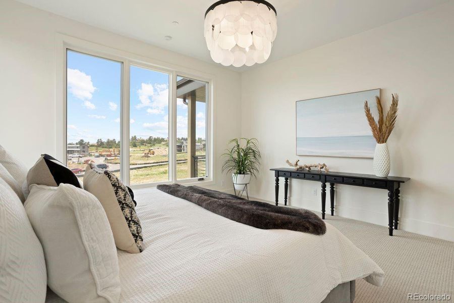 Primary bedroom with smooth drywall texture, bright picture windows, and soft plush carpeting for a serene retreat.