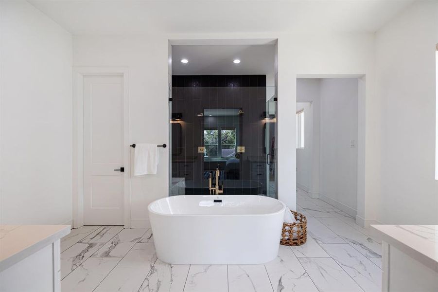 The en-suite bathroom is a spa-like sanctuary, equipped with a deep soaking tub, a walk-in shower with sleek glass doors, and dual vanities for ultimate convenience.