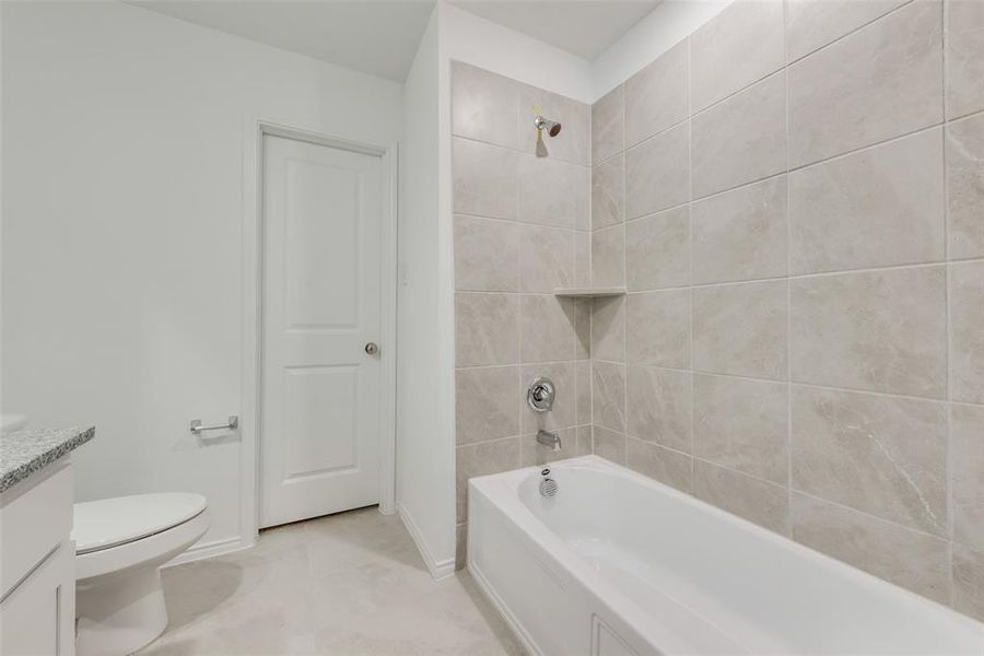 Full bathroom featuring tiled shower / bath combo, vanity, tile patterned floors, and toilet