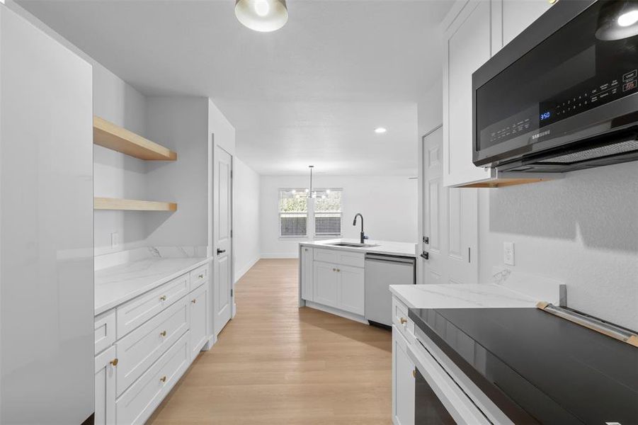 Kitchen featuring electric stove, light stone counters, white cabinets, an inviting chandelier, and stainless steel dishwasher