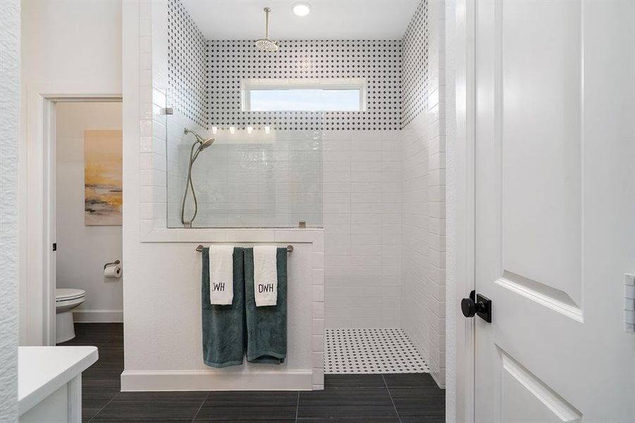 Large walk-in shower with rain shower head above as well as handheld shower. Gorgeous tile accent to ceiling.