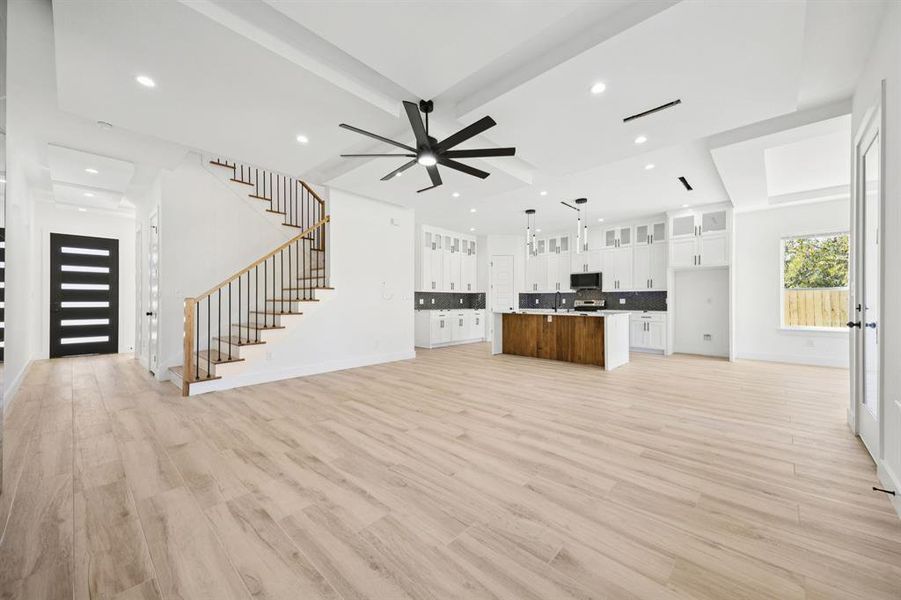 Unfurnished living room with light wood-type flooring, beam ceiling, stairs, recessed lighting, and a ceiling fan