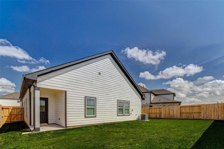 Step into a spacious backyard featuring a lush lawn and full privacy fencing, providing a perfect setting for outdoor activities, pets, or future landscaping ideas. The rear exterior of the home showcases clean lines and modern finishes, while the covered patio offers a shaded retreat. With plenty of room to personalize, this backyard is ready for entertaining, gardening, or relaxing under the Texas sky.