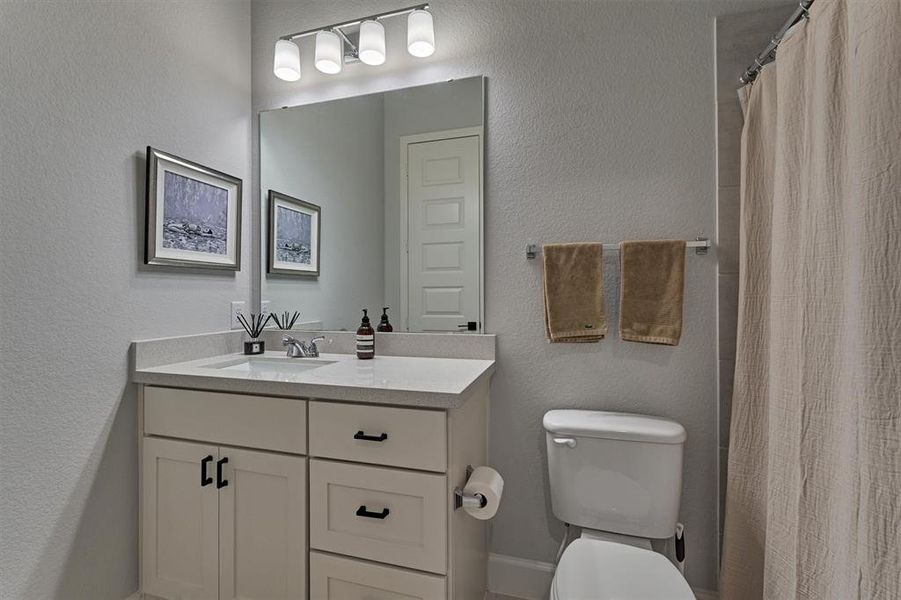 Shared full bath sits between bedrooms 3 and 4 with a tub/shower combo, raised quartz vanity and modern hardware. Note the linen closet for additional storage.