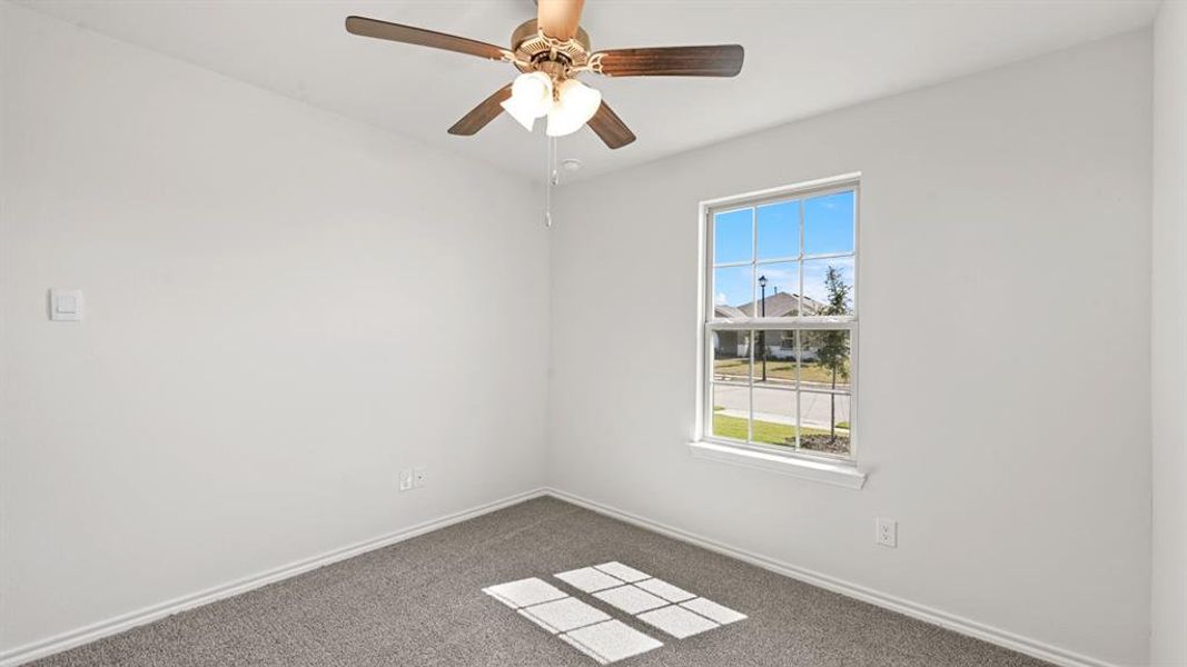 White wall interior featuring a ceiling fan with light fixture, single window with grid panes, and grey carpet flooring