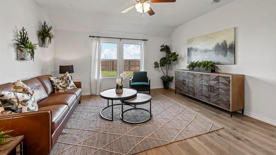 Living area with lofted ceiling, light wood finished floors, and ceiling fan