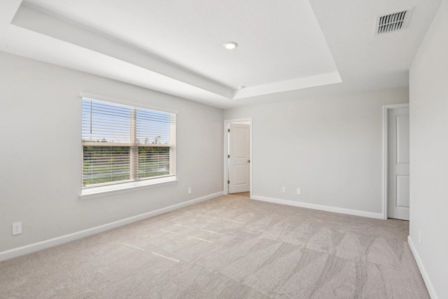 Spacious primary bedroom with a pond view