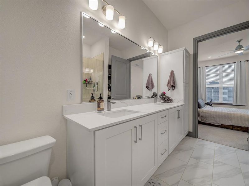 Ensuite bathroom with vanity, light marble finish flooring, and a ceiling fan Ensuite bathroom with vanity, light marble finish flooring, and a ceiling fan