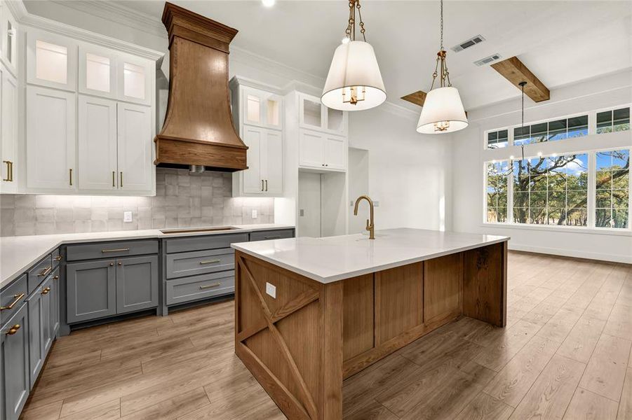 Kitchen with beamed ceiling, pendant lighting, backsplash, light stone countertops, and light wood finished floors Kitchen with beamed ceiling, pendant lighting, backsplash, light stone countertops, and light wood finished floors