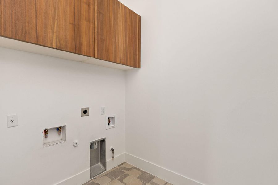 Ample wall cabinetry above the washer/dryer hookups defines this functional laundry space.