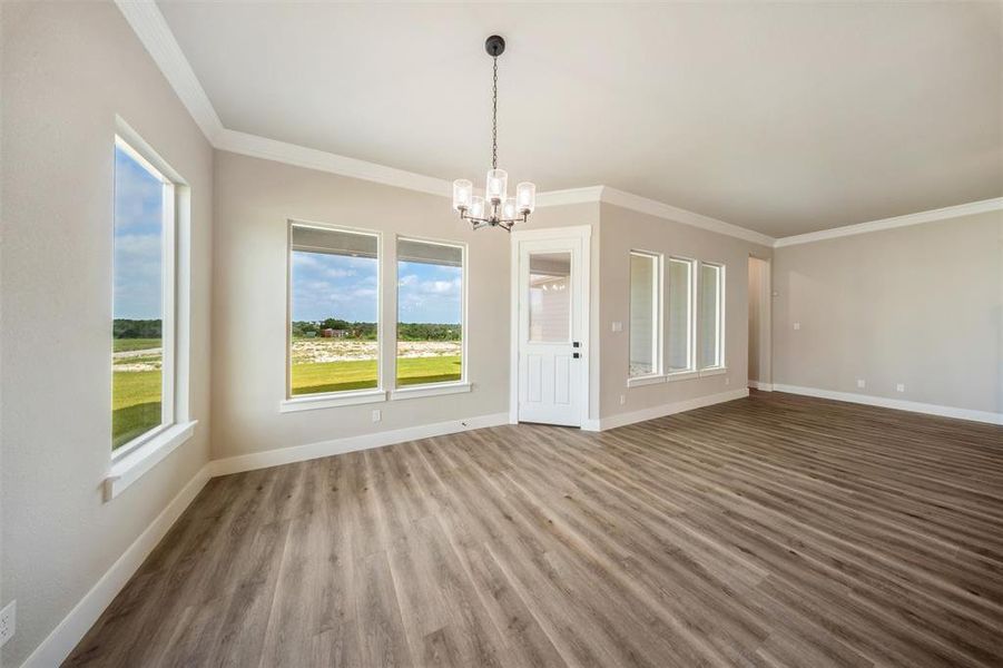 Unfurnished room with a chandelier, wood finished floors, and ornamental molding Unfurnished room with a chandelier, wood finished floors, and ornamental molding