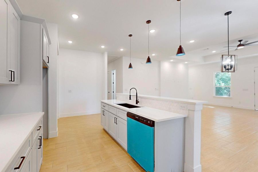Kitchen featuring decorative light fixtures, a kitchen island with sink, dishwashing machine, and open floor plan