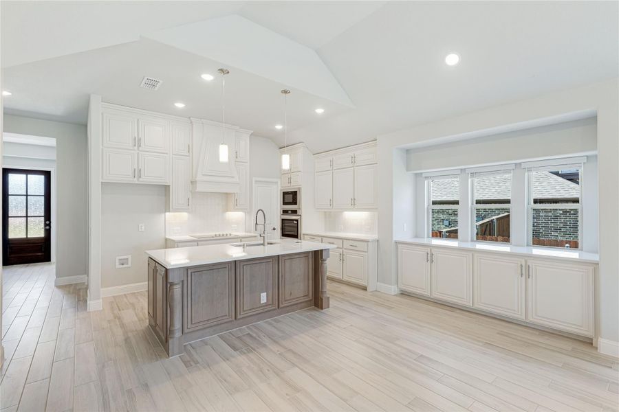 Open kitchen with white cabinets, gray wood island, white countertops, and light wood-look tile floors