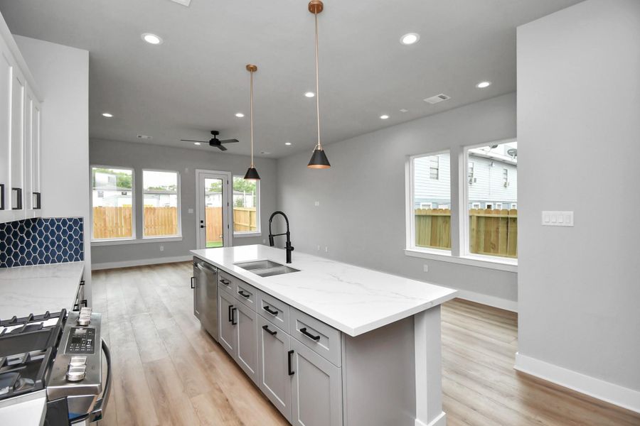 Modern kitchen featuring a large island, sleek finishes, and designer backsplash. Open layout connects seamlessly to the living area, ideal for entertaining.