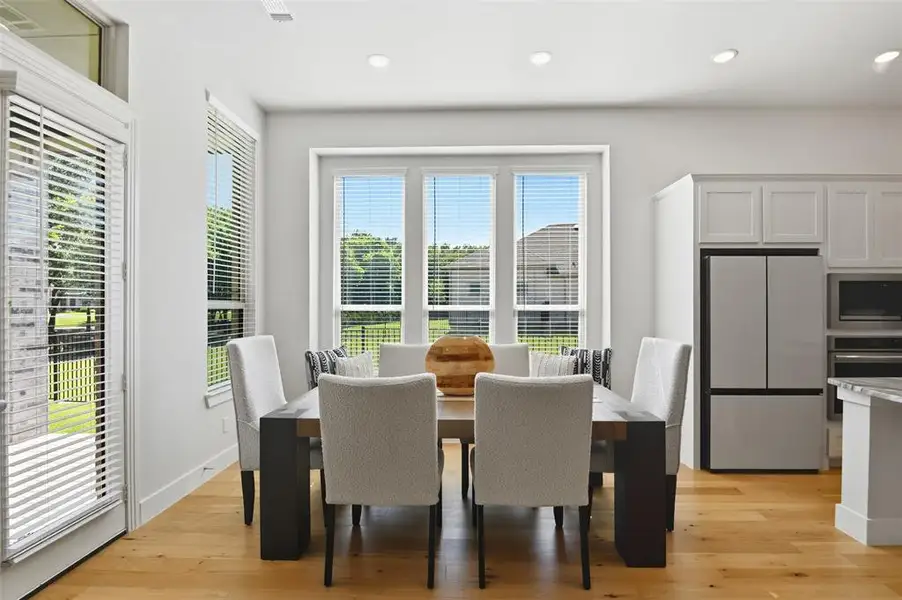 Dining area featuring light wood-finish flooring, recessed lighting, and a multi-panel window overlooking outdoor greenery Dining area featuring light wood-finish flooring, recessed lighting, and a multi-panel window overlooking outdoor greenery