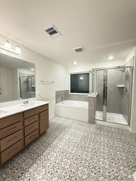 Updated master bath featuring dual vanity, soaking tub, separate walk-in shower, and designer tile flooring Updated master bath featuring dual vanity, soaking tub, separate walk-in shower, and designer tile flooring