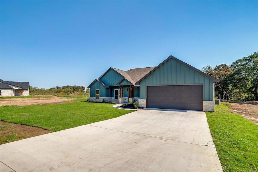 View of front of property featuring a garage and a front lawn