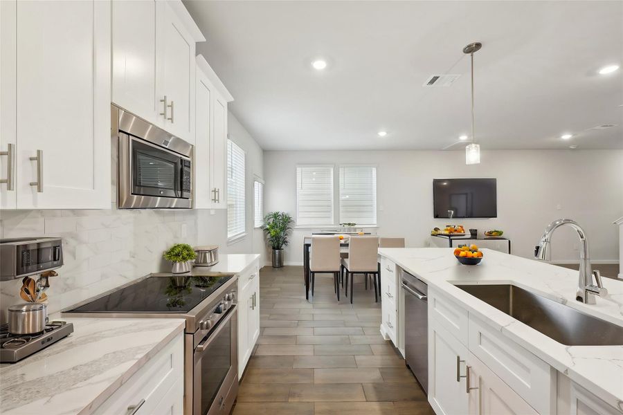 The contemporary kitchen features smooth white cabinets, a spacious island for additional preparation space, and modern fittings.